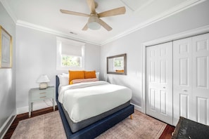 Um quarto com cama, mesa de cabeceira e ventilador de teto.