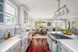 Una cocina moderna con armarios blancos, suelo de madera y un comedor con mesa y sillas.