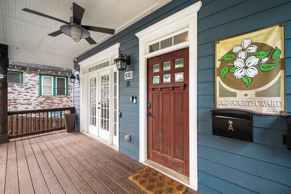 A porch with a wooden floor, a red door, and a mailbox.