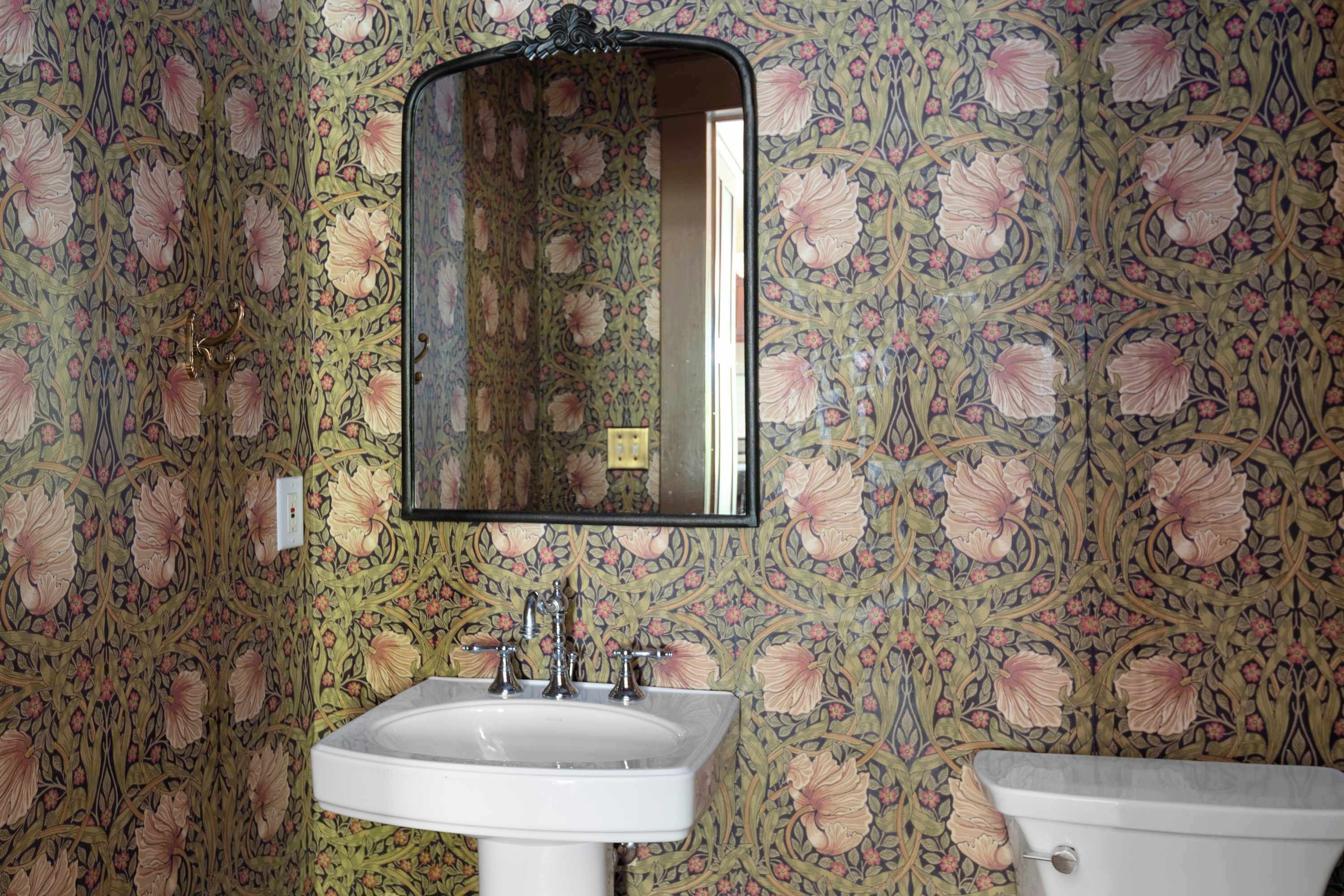 A bathroom with floral wallpaper, a white sink, and a toilet.