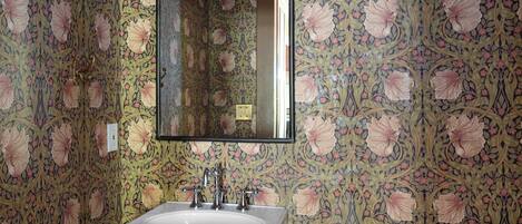 A bathroom with floral wallpaper, a white sink, and a toilet.