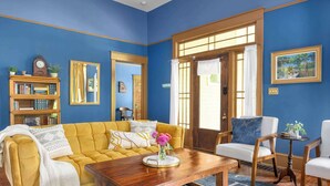 Una sala de estar con un sofá amarillo, una mesa de centro de madera y una pared azul.