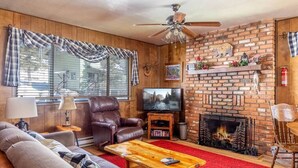 Una sala de estar acogedora con chimenea, sofá de cuero, televisor y una alfombra roja.