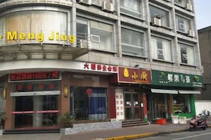 Un edificio con varias fachadas comerciales, incluyendo una con un letrero que dice 'Meng Jing'.