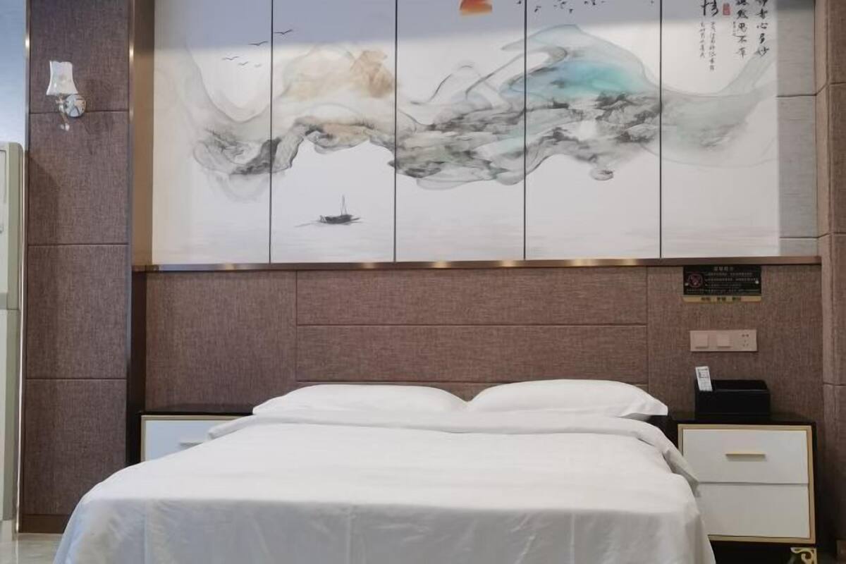 A hotel room with a bed, a nightstand, and a wall-mounted artwork.