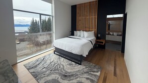 Quarto moderno com cama, ventilador de teto, uma janela grande e vista para o exterior.