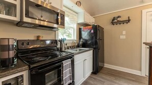 Una cocina moderna con electrodomésticos de acero inoxidable, armarios blancos y piso de madera.