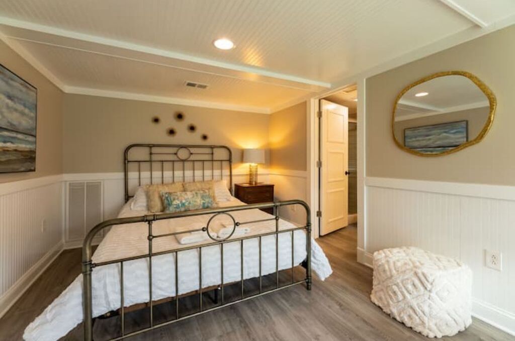 A bedroom with a metal bed frame, a bedside lamp, and a wall-mounted mirror.