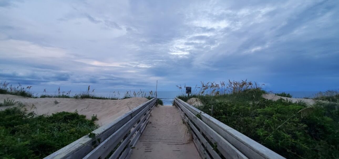 Ein Weg zum Strand mit Holzgeländer an beiden Seiten.