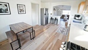 A modern kitchen with a wooden dining table, a refrigerator, and a coffee machine.