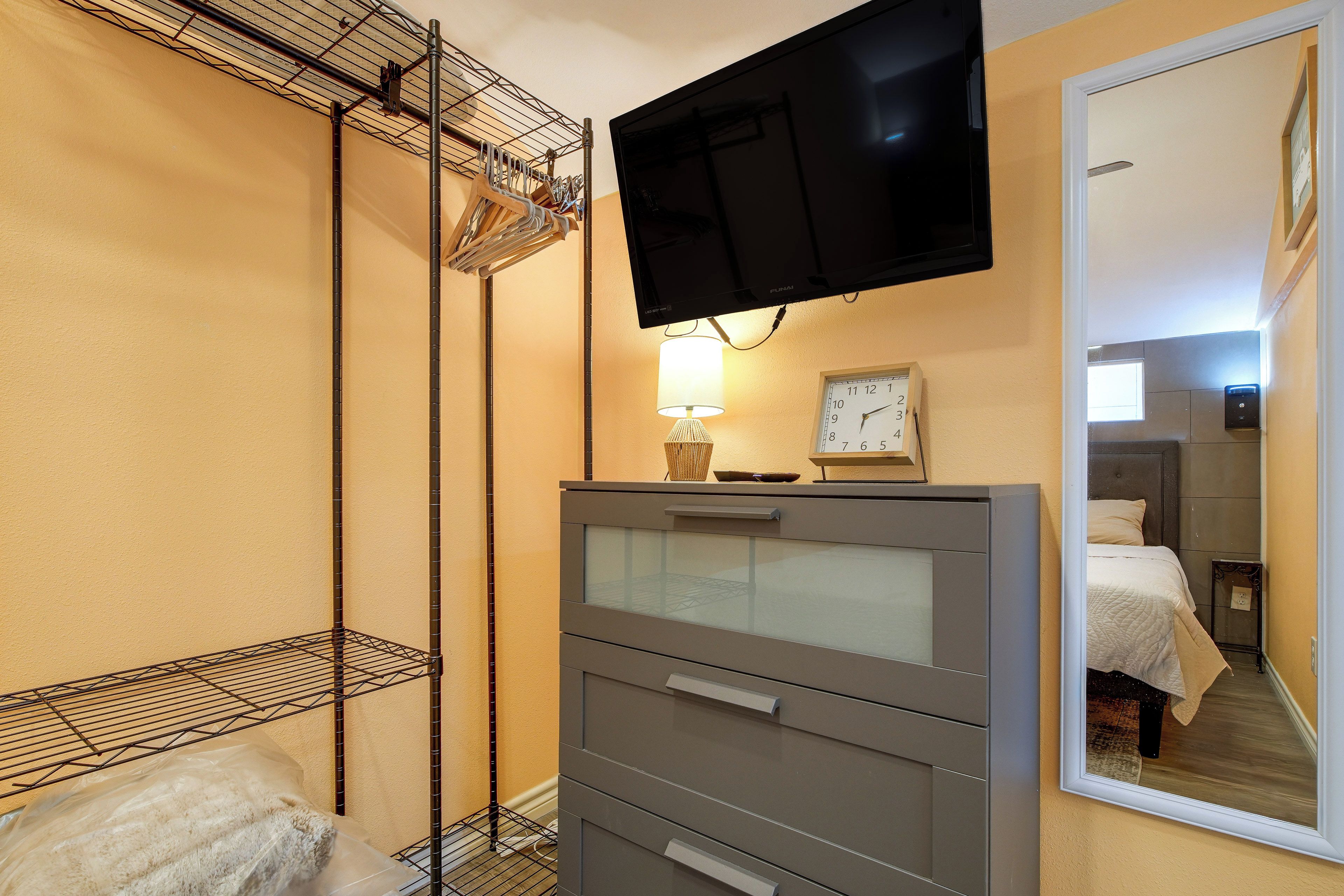 Une chambre d’hôtel comprenant un lit, une commode, un téléviseur fixé au mur, un miroir et une lampe.