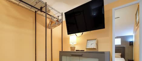 Une chambre d’hôtel comprenant un lit, une commode, un téléviseur fixé au mur, un miroir et une lampe.