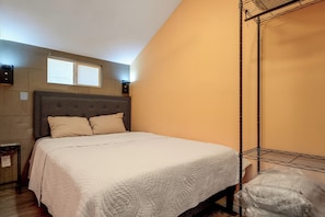 Ein Schlafzimmer mit einem Bett, einem Kopfteil, einem Fenster und einem an der Wand befestigten Regal.