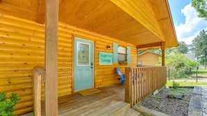 Eine Holzhütte mit Veranda, einer Tür mit der Aufschrift 'Sugarfoot Cottage' und einer kleinen Sitzgelegenheit im Freien.