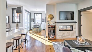 Una cocina moderna con barra, chimenea y comedor con luz natural.