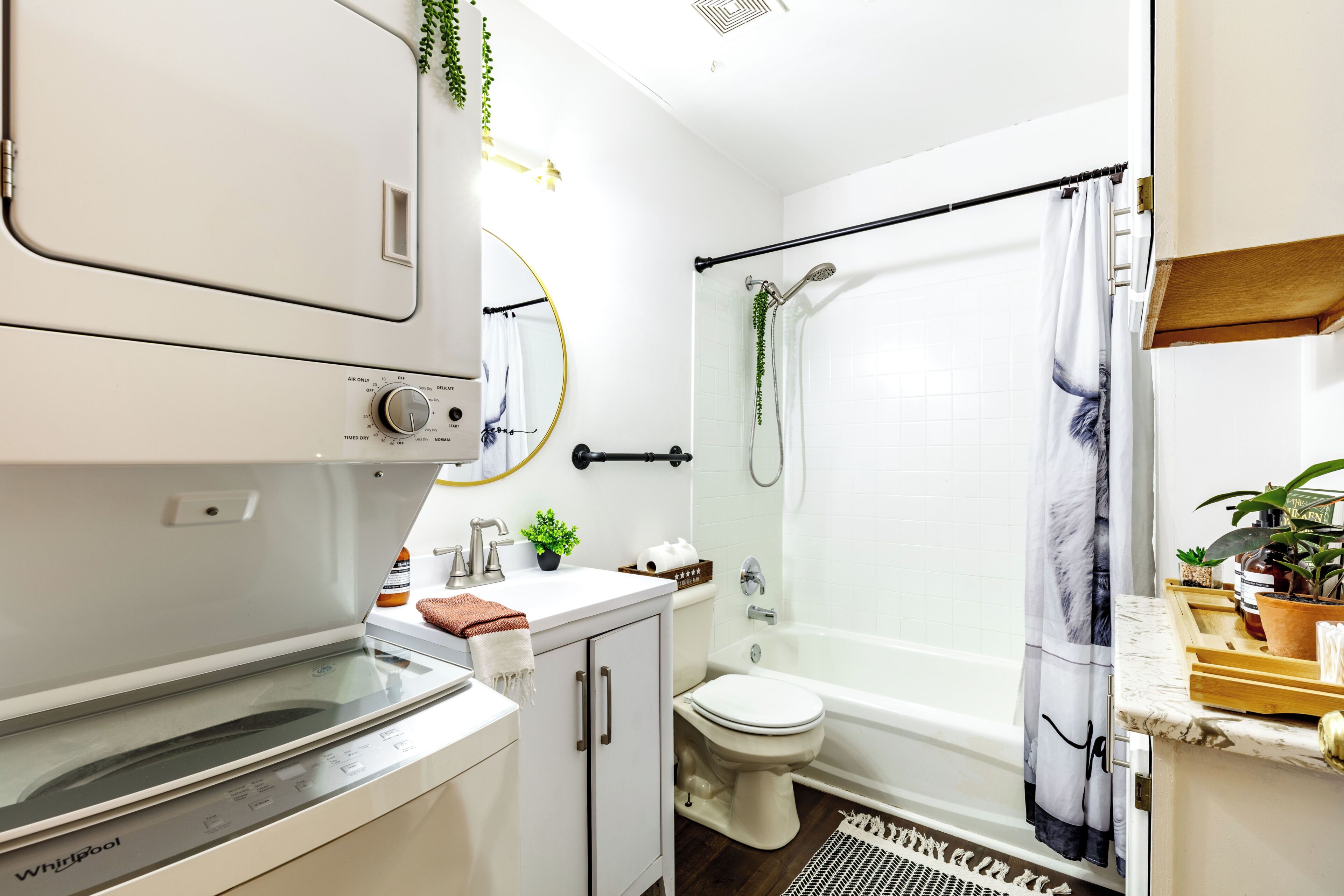 Ein modernes Badezimmer mit Waschmaschine, Toilette, Badewanne und Dusche.
