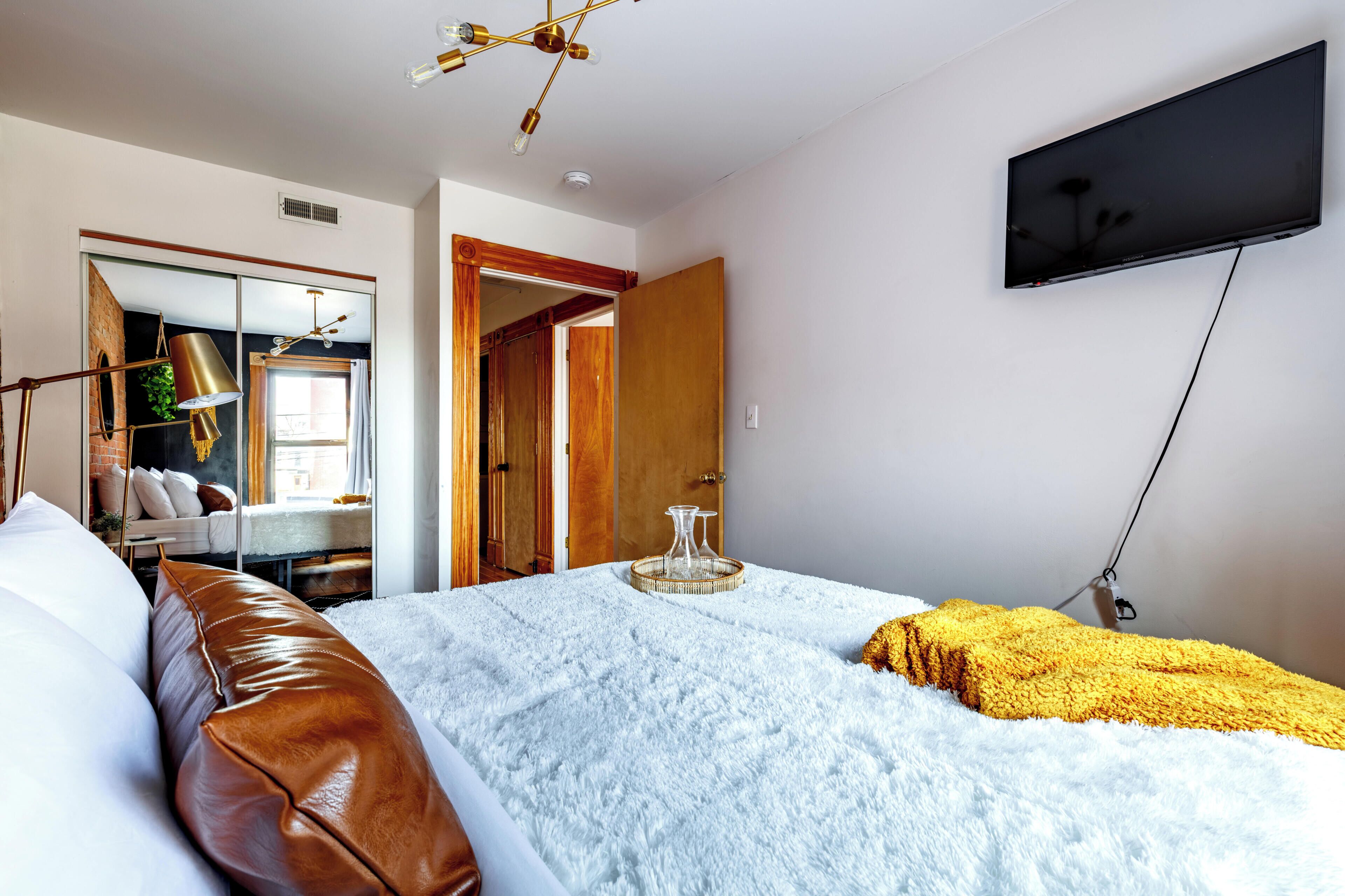 Una camera da letto con un letto, una TV a parete, un armadio e uno specchio.
