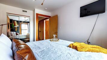 Una camera da letto con un letto, una TV a parete, un armadio e uno specchio.