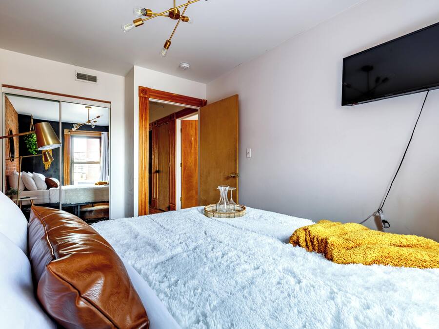 Una camera da letto con un letto, una TV a parete, un armadio e uno specchio.