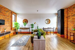 A living room with a sofa, coffee table, and potted plants. - Jungle House Luxury Lofts – Short North High Street (Columbus)