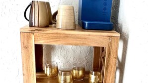 Una estantería de madera con utensilios de cocina y cristalería.