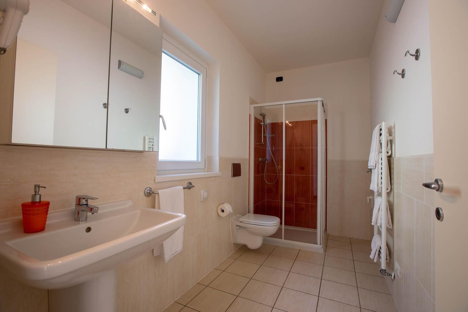 A modern bathroom with a sink, toilet, and glass-enclosed shower.