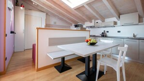 Une cuisine moderne dotée d’une verrière, de meubles blancs et d’un coin repas avec une table et des chaises.