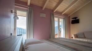 Une chambre d’hôtel avec un lit, une table de chevet, un téléviseur fixé au mur et une fenêtre avec des rideaux.