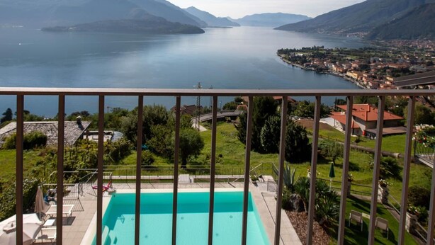 Un balcon avec une piscine donnant sur un lac et des montagnes.