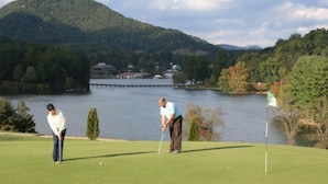 A golf course with a lake and mountains in the background.