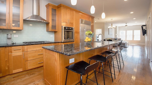 Een moderne keuken met houten kastjes, roestvrijstalen apparatuur en een granieten aanrecht.