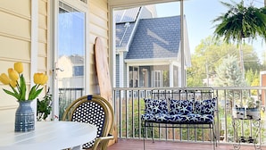 Eine überdachte Terrasse mit Tisch, Stühlen, Deckenventilator und Blick auf ein Haus.