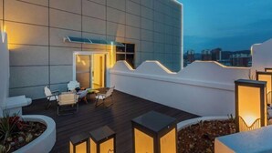 A modern building with a flat roof, outdoor seating area, and a view of the cityscape. - Huaning Hotel (Huaning)