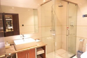 Un baño moderno con ducha de vidrio, lavamanos grande y espejo.