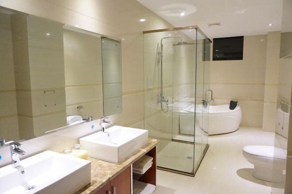 Un baño moderno con ducha de vidrio, una bañera grande y dos lavamanos.