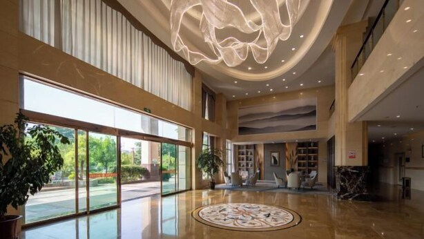 A spacious lobby with a high ceiling, large windows, and a central decorative light fixture. - Huaning Hotel (Huaning)