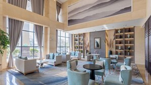 A spacious lobby with a high ceiling, large windows, and a variety of seating arrangements including sofas and armchairs. - Huaning Hotel (Huaning)