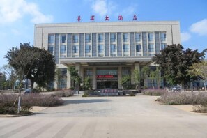 Un edificio moderno con una entrada amplia, un cartel con caracteres chinos y un cielo despejado.