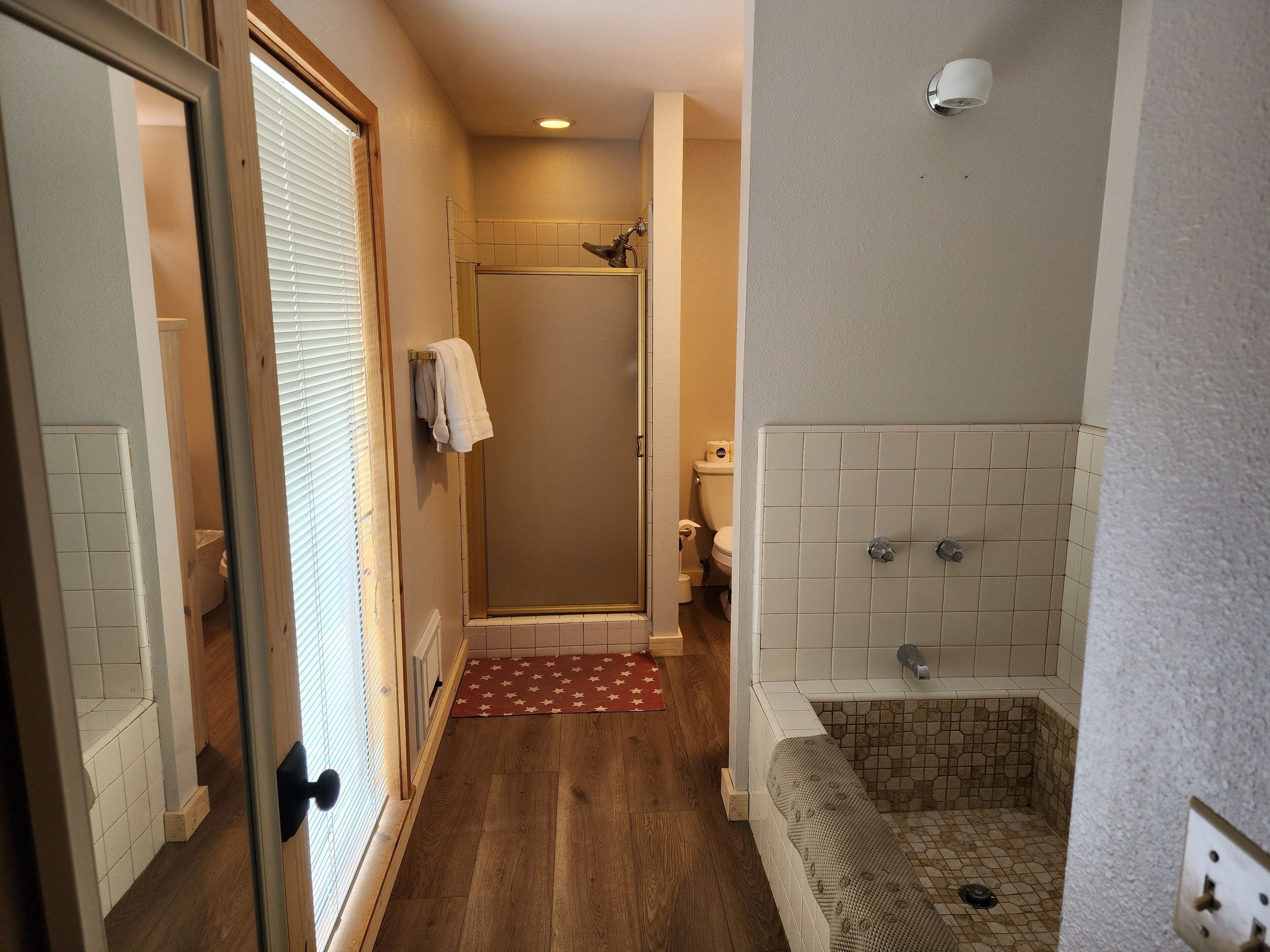 A bathroom with a shower, toilet, and a tiled floor.