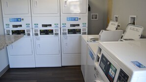 A laundry room with multiple stacked washing machines and dryers. - Noble Suites Jacksonville (Jacksonville)