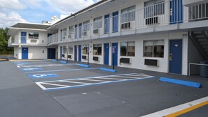 A motel with multiple rooms, a parking lot with handicapped parking spaces, and a staircase leading to the upper floor. - Noble Suites Jacksonville (Jacksonville)