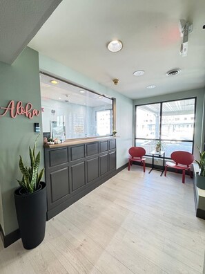 A reception area with a counter, two red chairs, a large window, and a sign that reads "Aloha".