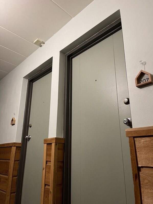 Two doors with wooden trim and a small wooden number display.