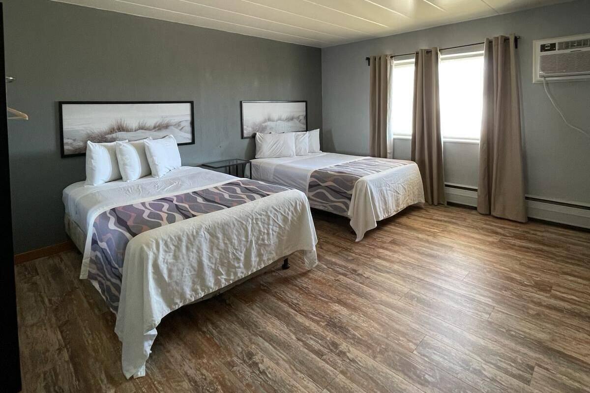 Una habitación de hotel con dos camas, una televisión de pantalla plana y un equipo de aire acondicionado.