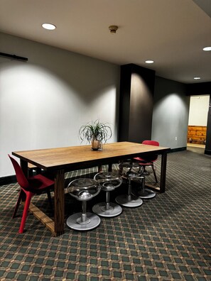 A conference room with a wooden table, red chairs, and a potted plant.