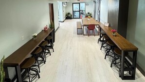 Un salón de conferencias con mesas largas y sillas, un banco y plantas en macetas.