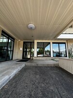 Un espacio al aire libre cubierto con suelo de hormigón, ventanas amplias y techo con diseño de cuadrícula.
