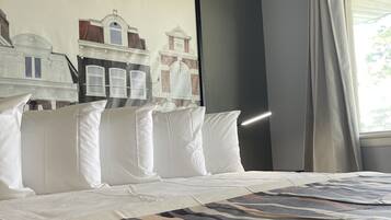 Habitació d'hotel amb un llit gran, un quadre de paisatge urbà a la paret i una finestra amb cortines.