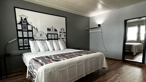 Un dormitorio con cama, un cuadro grande enmarcado en la pared y suelo de madera.