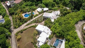 An aerial view of a residential area with houses, a swimming pool, and a view of the ocean. - Playa del Coco Hillside Villa • 4BR • Infinity Pool • Bay & Ocean Views (Guanacaste Province)